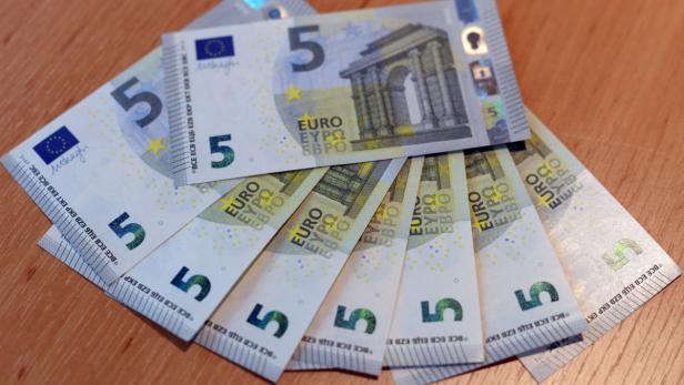 Mehrere 5-Euro-Scheine liegen auf einem Tisch.