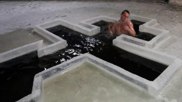 Ein Mann badet in einem eisigen Becken in Form eines Kreuzes.