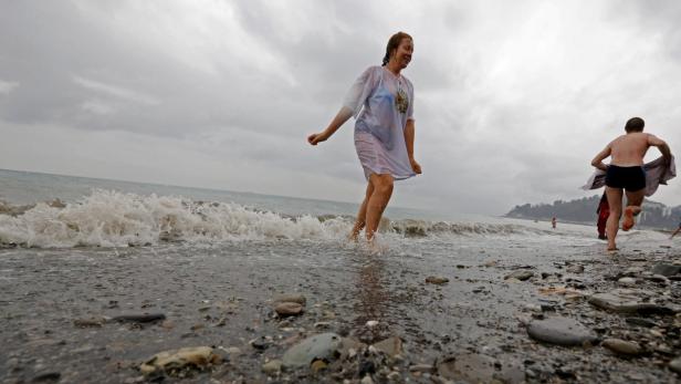 Eine Frau läuft an einem bewölkten Tag ins Meer.