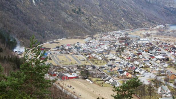 Blick auf ein norwegisches Dorf in einem Tal mit Bergen im Hintergrund.