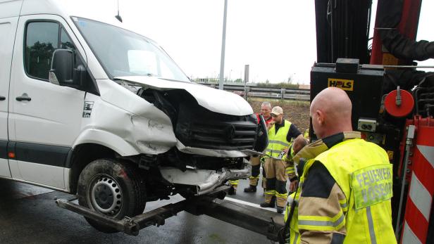 Ein beschädigter weißer Transporter wird von Feuerwehrleuten geborgen.