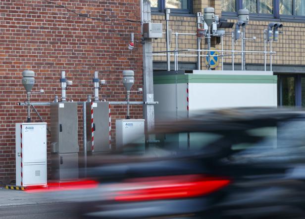 Eine Anlage zur Luftqualitätsmessung steht an einer Straße, während ein Auto vorbeifährt.