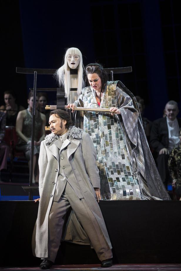 Szene aus einer Opernaufführung mit zwei Sängern und einer weißen Maske.