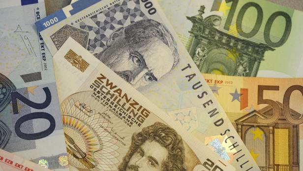 Verschiedene Euro-Banknoten und alte österreichische Schilling-Banknoten liegen übereinander.