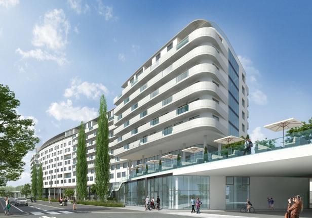 Ein modernes, weißes Wohngebäude mit abgerundeten Balkonen und einer Dachterrasse unter blauem Himmel.