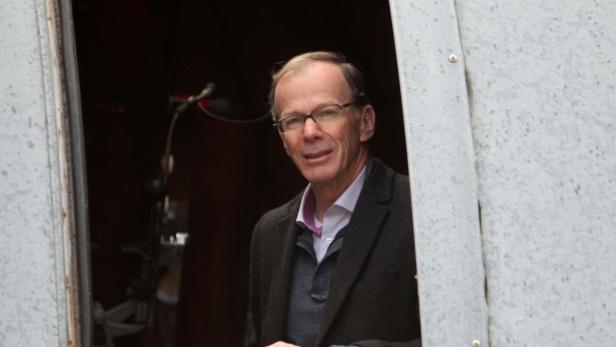 Ein Mann mit Brille schaut aus einer grauen Tür.