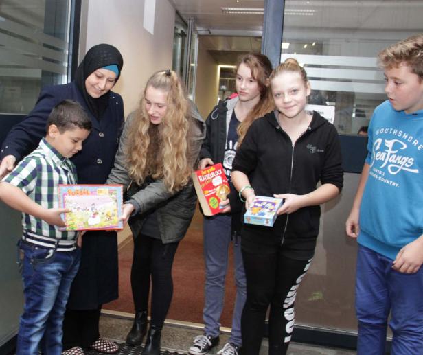 Eine Gruppe von Kindern und eine Frau tauschen Puzzles und Bücher aus.