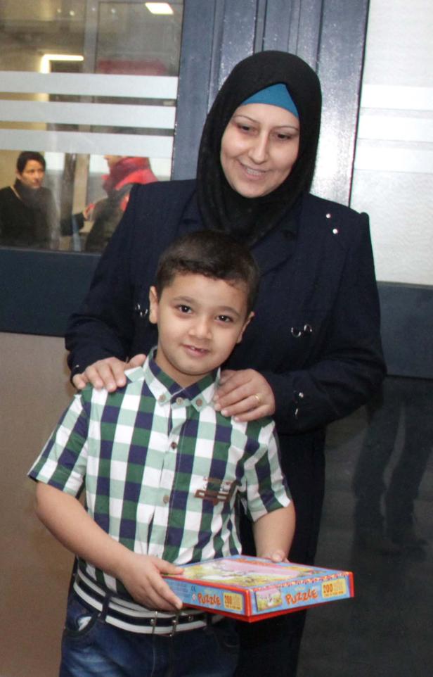 Eine Frau mit Hijab und ein Junge halten eine Puzzle-Schachtel.