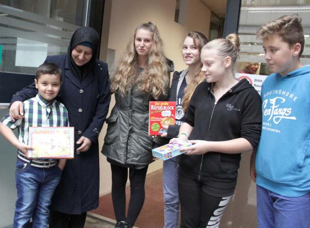 Eine Gruppe von Kindern und eine Frau halten Spiele und einen Rätselblock in den Händen.