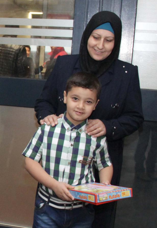 Eine Frau mit Hijab und ein Junge halten eine Puzzle-Schachtel.
