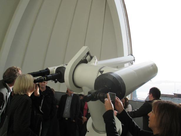 Besucher betrachten den Himmel durch ein großes Teleskop in einer Sternwarte.