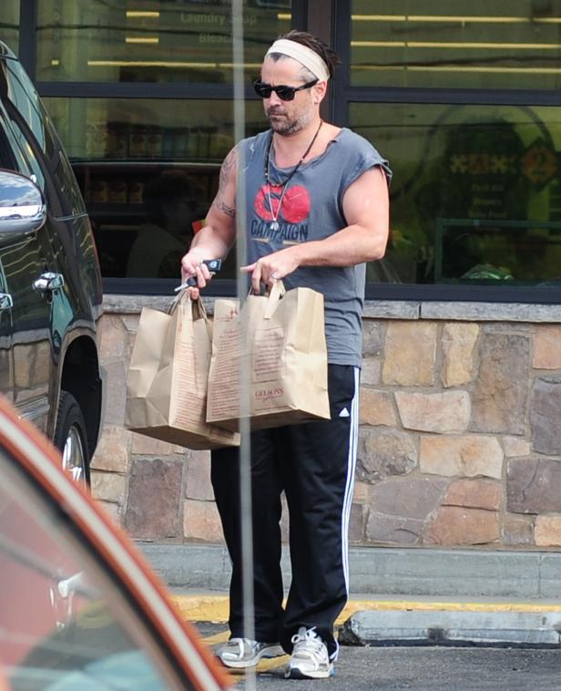 Colin Farrell trägt Einkaufstüten vor einem Geschäft.