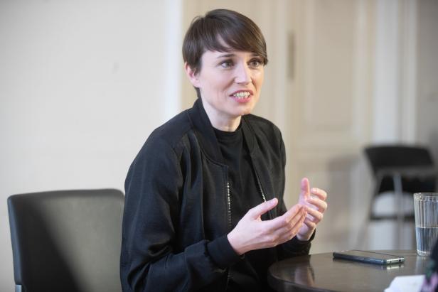 Eine Frau mit kurzem braunem Haar gestikuliert während eines Gesprächs.