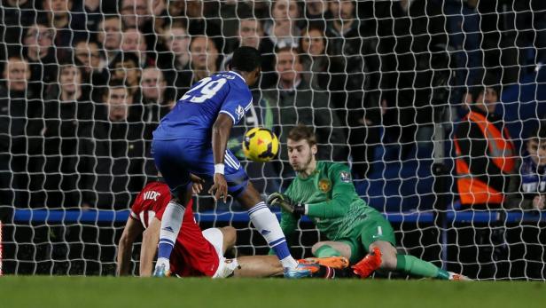 Ein Fußballspieler schießt den Ball, während der Torwart versucht, ihn abzuwehren.