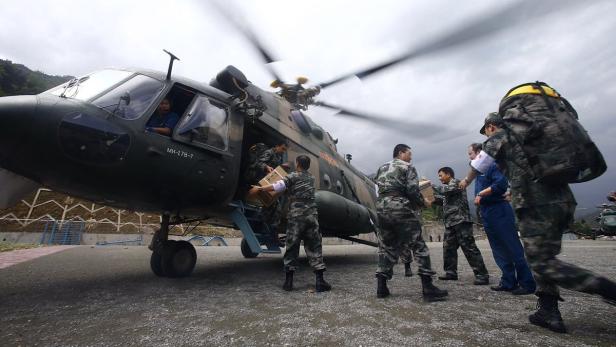 Militärpersonal entlädt Hilfsgüter aus einem Hubschrauber vom Typ Mil Mi-17.