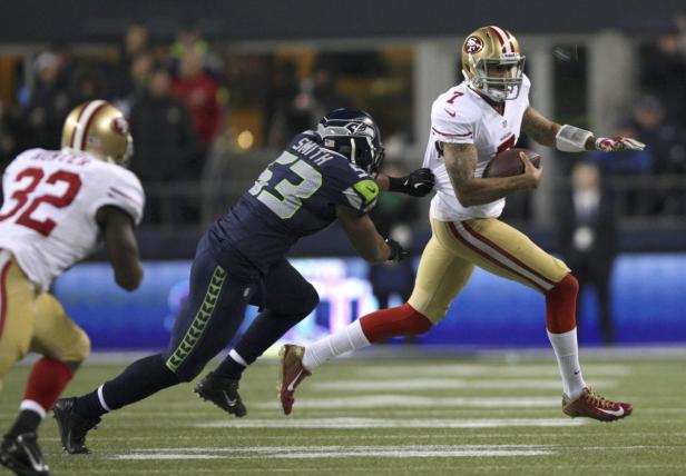 Ein Quarterback der 49ers läuft mit dem Ball, während ein Verteidiger der Seahawks ihn verfolgt.