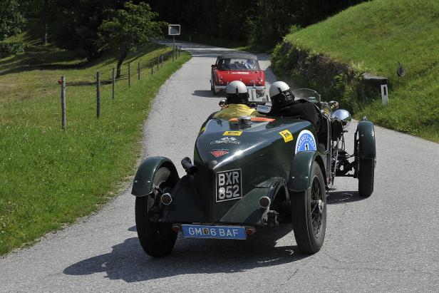 Zwei Oldtimer nehmen an einer Rallye auf einer Landstraße teil.