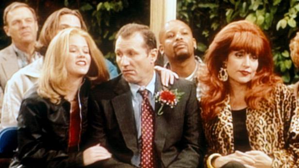 Al, Peggy, Kelly und Freunde sitzen im Publikum, möglicherweise bei einer Hochzeit.