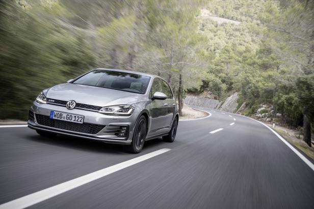 Ein silberner VW Golf fährt auf einer kurvenreichen Straße.