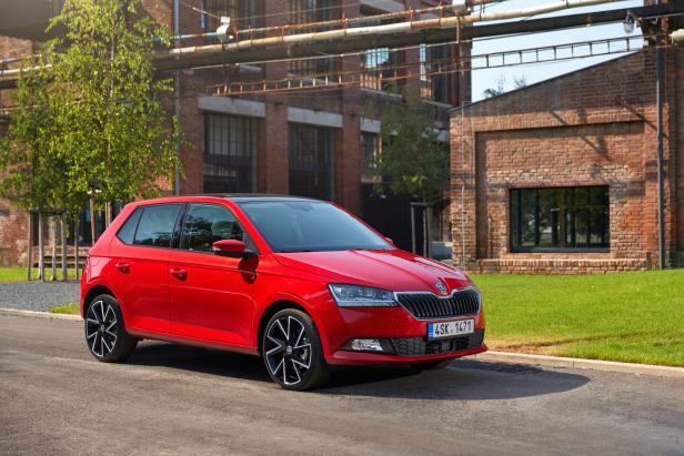 Ein roter Škoda Fabia steht vor einem Backsteingebäude.
