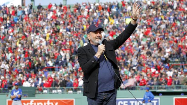 Neil Diamond singt vor einer großen Menschenmenge im Stadion.