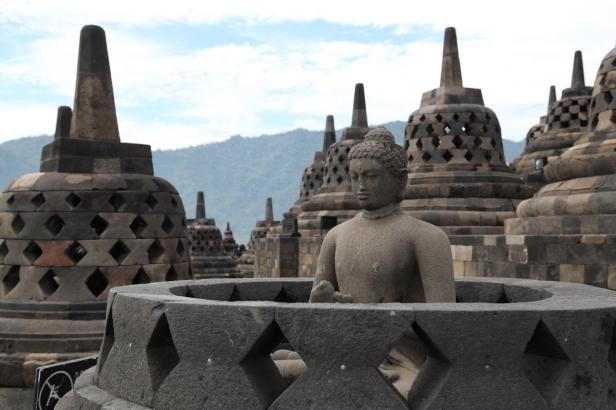 Eine Buddha-Statue inmitten der Stupas von Borobudur in Indonesien.