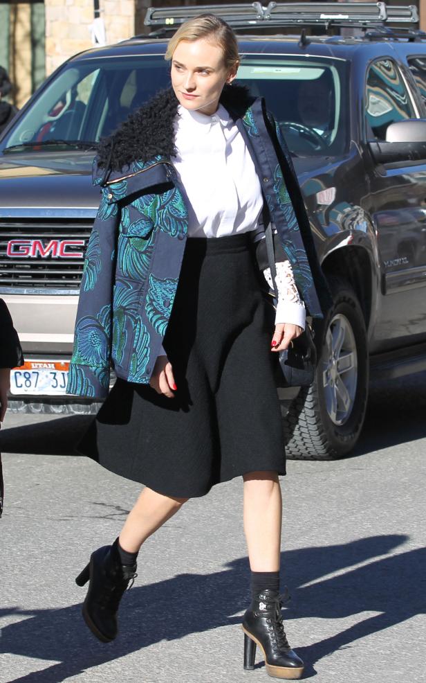 Diane Kruger trägt einen gemusterten Blazer, einen schwarzen Rock und Stiefeletten.