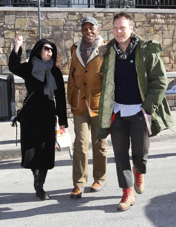 Danny Glover mit zwei Begleitern auf einer sonnigen Straße.
