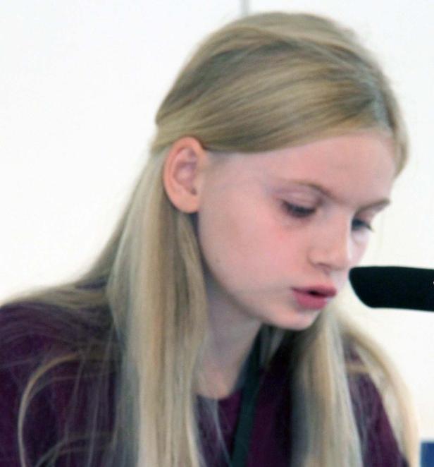 Eine junge Frau mit blonden Haaren spricht in ein Mikrofon.