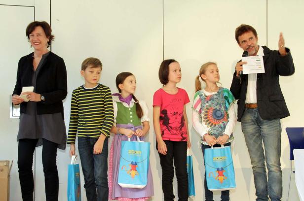 Eine Frau und ein Mann stehen mit vier Kindern auf einer Bühne.