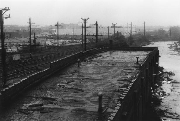 Ein verlassenes Gebäude mit Blick auf Bahngleise und eine Stadt im Hintergrund.
