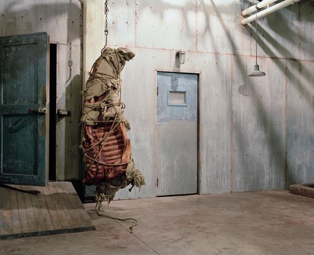 Ein großes Stück Fleisch, in Stoff gehüllt und mit Seil verschnürt, hängt in einem Kühlraum.