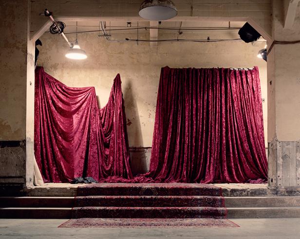 Eine Bühne mit rotem Samtvorhang und einem Teppich auf den Stufen.