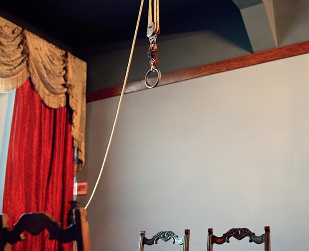 Ein Seilzugsystem hängt vor einer Wand und einem roten Vorhang.