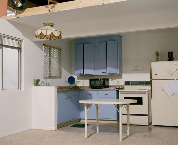 Eine Küche mit blauen Schränken, einem weißen Kühlschrank und einem kleinen Tisch.