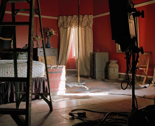 Ein Schlafzimmer mit roter Wandfarbe, einer Stange und Filmrequisiten.