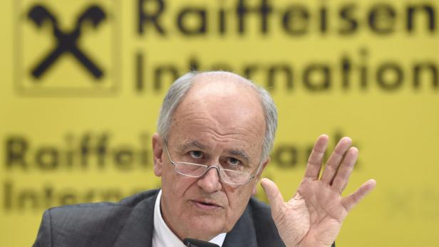 Ein Mann mit Brille gestikuliert vor einem Raiffeisen International Hintergrund.