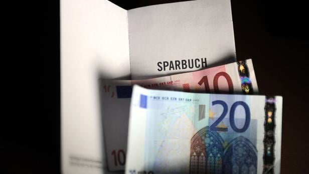 Ein Sparbuch mit einem 10-Euro-Schein und einem 20-Euro-Schein.