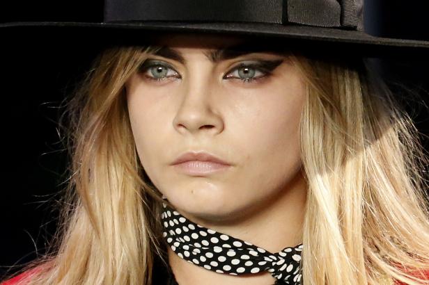 Nahaufnahme von Cara Delevingne mit Hut und gepunktetem Halstuch.