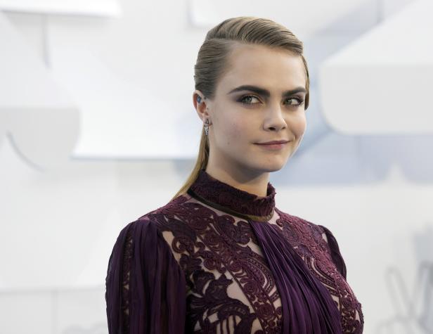 Cara Delevingne in einem bordeauxroten Kleid mit Spitze.
