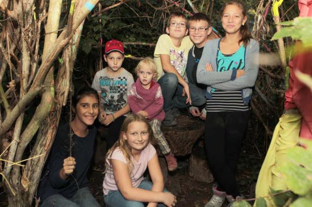 Eine Gruppe von Kindern posiert in einem Waldstück für ein Foto.