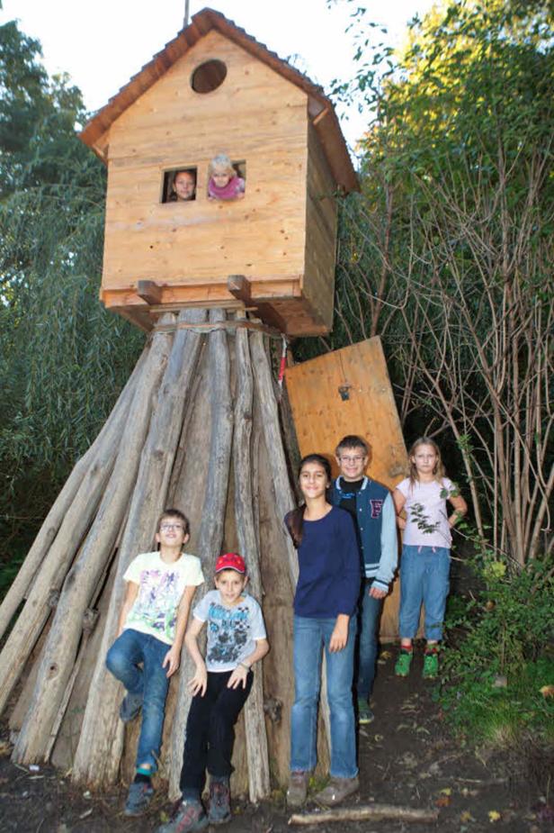 Eine Gruppe Kinder steht vor und in einem Baumhaus.