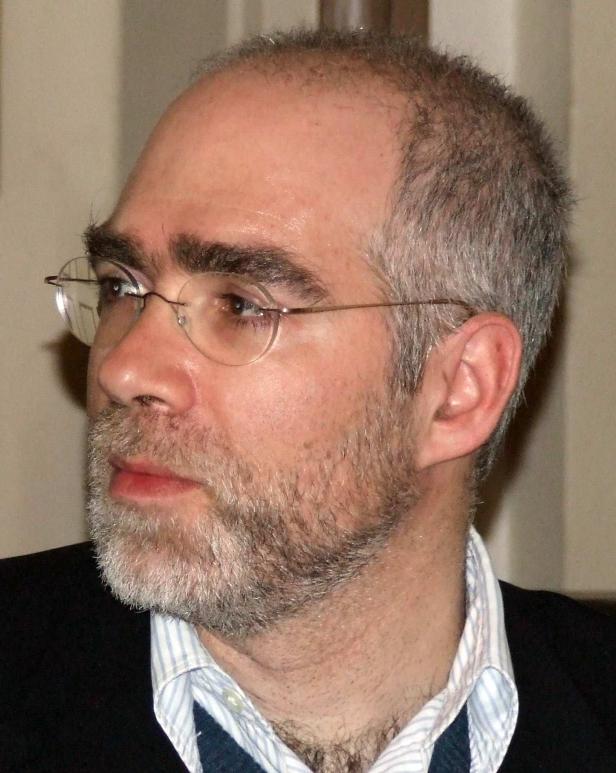 Ein Mann mit Brille und grauem Bart schaut zur Seite.