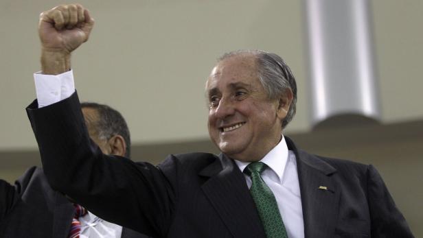 Ein älterer Mann im Anzug ballt die Faust und lächelt.