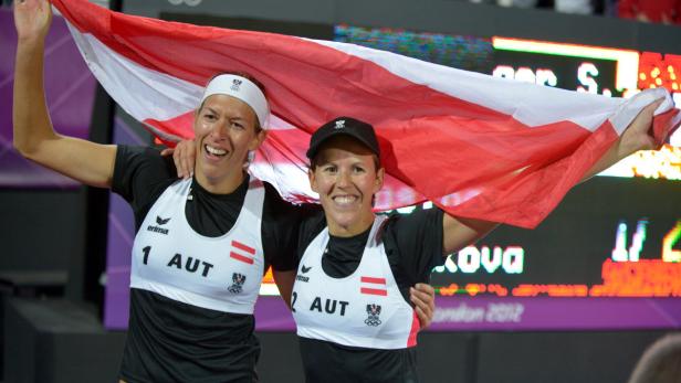 Zwei Beachvolleyballspielerinnen aus Österreich feiern mit der österreichischen Flagge.