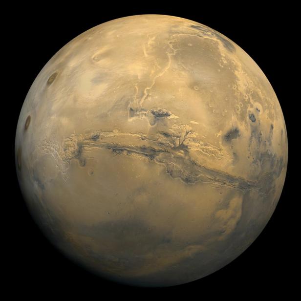 Eine Ansicht des Planeten Mars mit seiner rötlichen Oberfläche und markanten Schluchten.