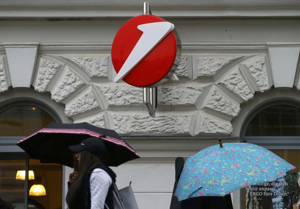 People carrying umbrellas pass a Bank Austria branch office in Vienna