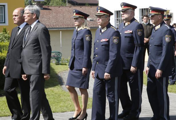 Eine Gruppe von Personen, darunter mehrere in Polizeiuniformen, geht nebeneinander her.
