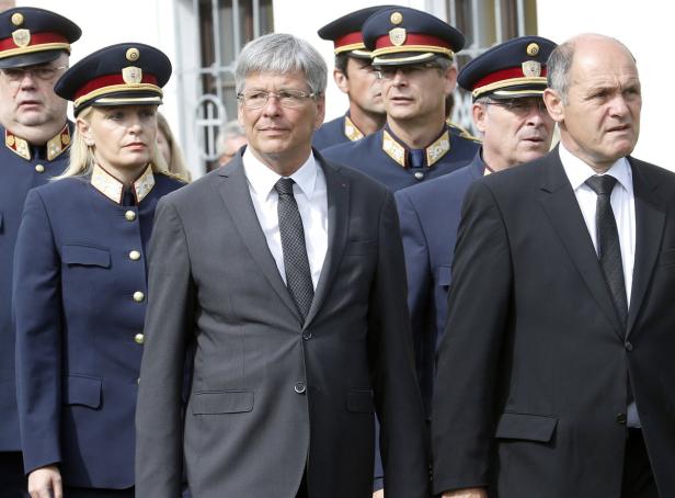 Eine Gruppe von Personen in Anzügen und Uniformen steht zusammen.