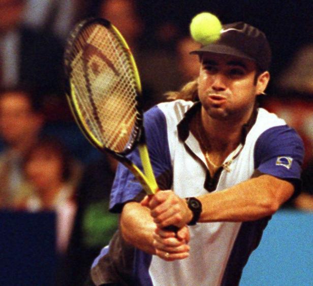 Andre Agassi beim Tennisspielen mit einem Ball auf seiner Mütze.